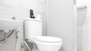 Une salle de bain moderne avec des toilettes blanches, un lavabo et un espace douche.