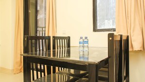 Una mesa de comedor con cuatro sillas, dos botellas de agua y una ventana con cortinas.