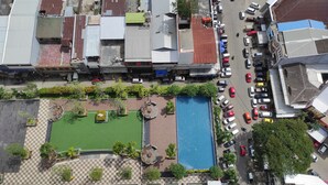 An aerial view of a commercial area with a swimming pool, parking lot, and various buildings.