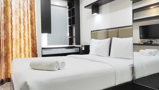 A hotel room with a large bed, a bedside table, a mirror, and a TV.