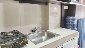 A kitchen with a gas stove, stainless steel sink, and white cabinets.