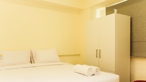 Una habitación de hotel con una cama, un armario y un taburete rojo.