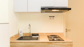 Una cocina con un lavabo, una estufa y un armario superior.