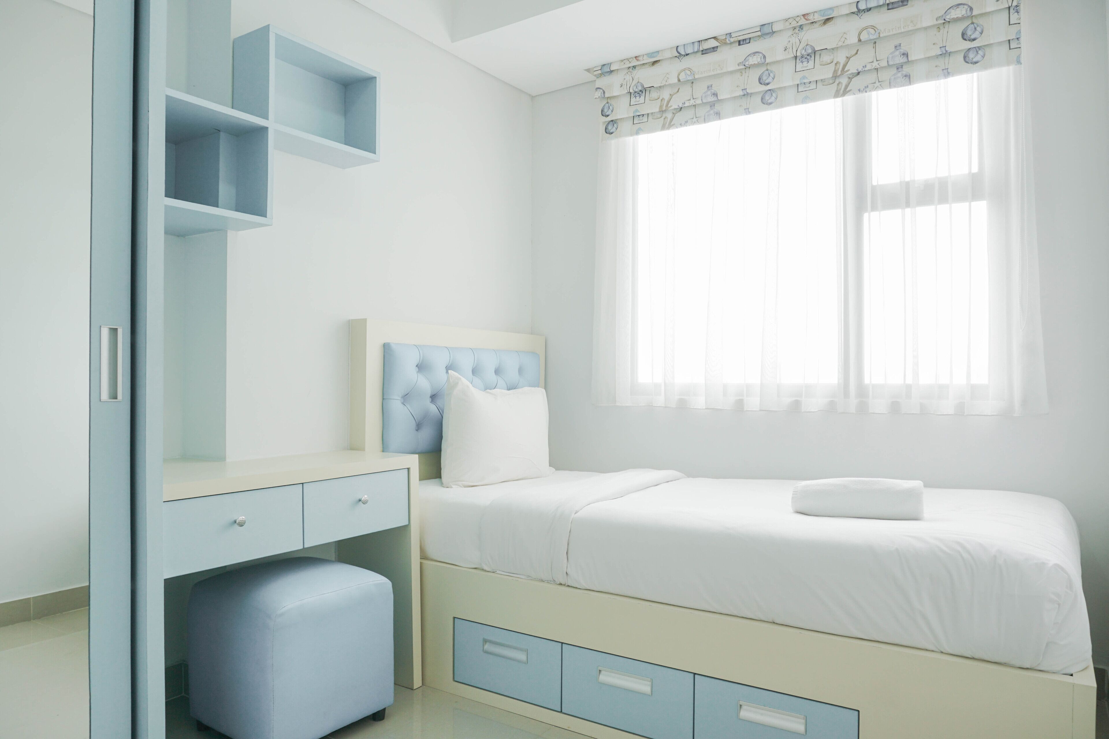 A bedroom with a bed, a desk, and a wardrobe.