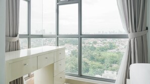 A room with a large window, a white dresser, and a view of a cityscape. - Warm And Cozy 3Br Apartment At The Royal Olive Residence (Jakarta)