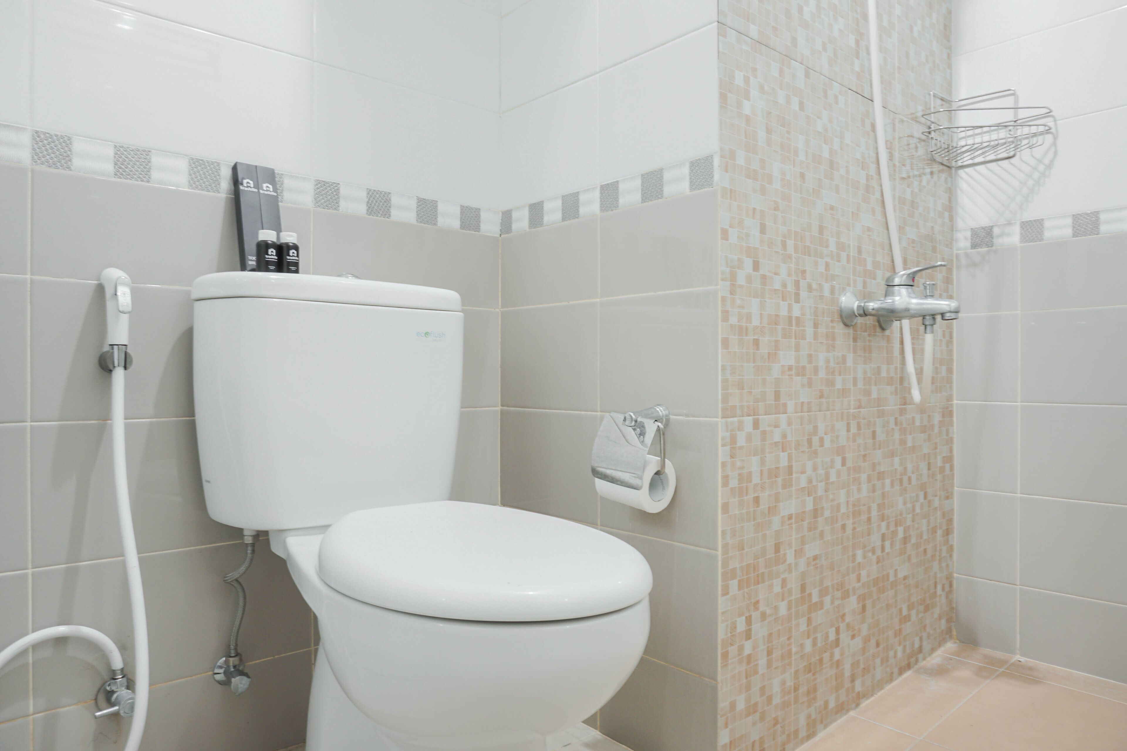 A bathroom with a toilet, a shower, and a toilet paper holder.