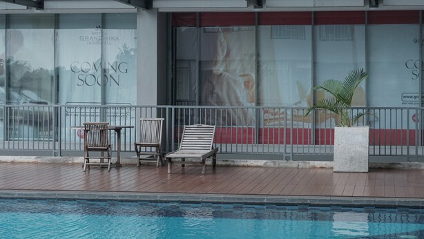 A hotel with a pool area, including lounge chairs and a potted plant. - Warm And Cozy 3Br Apartment At The Royal Olive Residence (Jakarta)