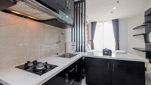 A modern kitchen with a gas stove, a coffee machine, and a sink. - Cozy And Tidy Studio Apartment Mangga Dua Residence (Jakarta)