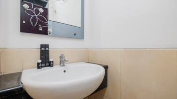 Un baño con lavamanos blanco, encimera negra y espejo encima.