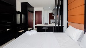 A hotel room with a bed, a desk, a television, and a wardrobe. - Cozy And Tidy Studio Apartment Mangga Dua Residence (Jakarta)