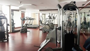 A gym with cardio machines, weight equipment, and mirrors on the walls. - Cozy And Tidy Studio Apartment Mangga Dua Residence (Jakarta)