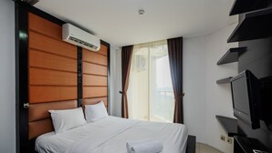 A hotel room with a bed, a TV, and an air conditioning unit. - Cozy And Tidy Studio Apartment Mangga Dua Residence (Jakarta)
