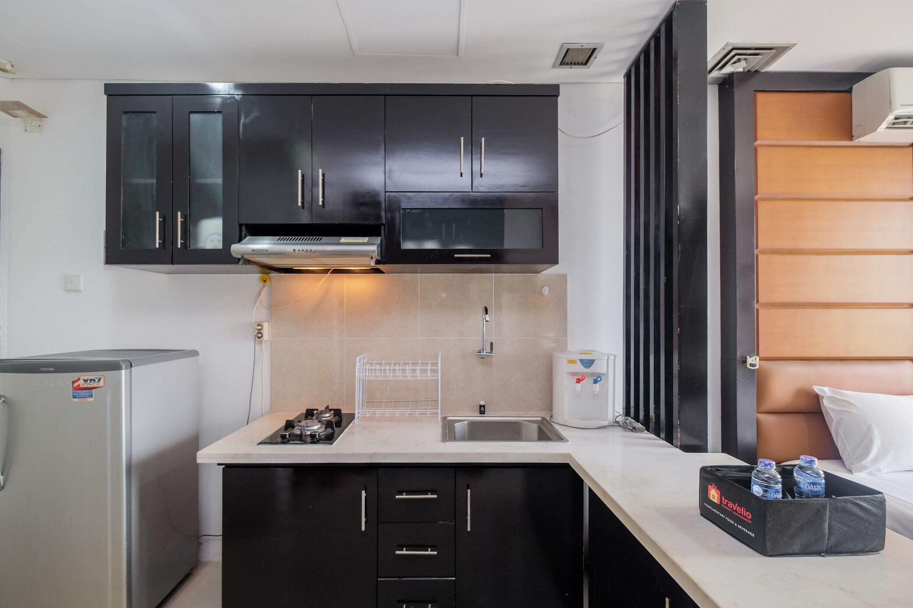 A compact kitchen with dark cabinets, a microwave, a sink, and a refrigerator.