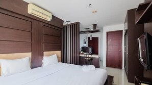 Una camera d'albergo con un letto grande, una televisione, una scrivania con una sedia e un armadio.