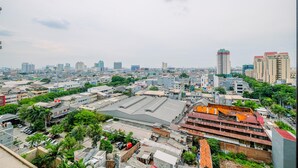 A cityscape with various buildings, including a large industrial area with warehouses and a tall skyscraper in the distance. - Best Deal Studio Apartment At Mangga Dua Residence (Jakarta)