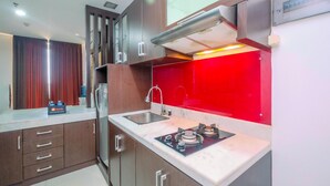 A modern kitchen with a gas stove, stainless steel sink, and wooden cabinets. - Best Deal Studio Apartment At Mangga Dua Residence (Jakarta)