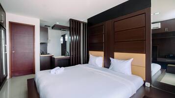 Una habitación de hotel moderna con una cama grande, cabecero de madera, mesita de noche y armario empotrado.