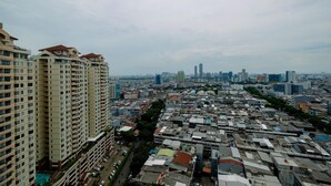 A high-rise building with multiple balconies and a dense urban area with various buildings in the background. - Comfort And Homey Studio Apartment At Mangga Dua Residence (Jakarta)