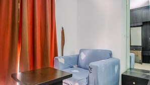A room with a blue sofa, a wooden table, a mirror, and a red curtain. - Cozy Living Studio Apartment Mangga Dua Residence Near Itc Mall (Jakarta)