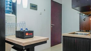 A kitchen with a water dispenser, a sink, and a table with a box labeled 'travelio'. - Cozy Living Studio Apartment Mangga Dua Residence Near Itc Mall (Jakarta)