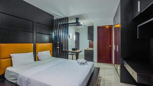 A hotel room with a large bed, a desk, a mirror, and a TV. - Cozy Living Studio Apartment Mangga Dua Residence Near Itc Mall (Jakarta)