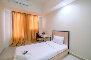 A hotel room with a bed, a desk, and a chair.