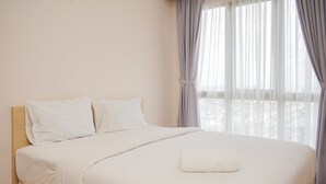 A neatly made bed with white linens and a single white pillow, a window with sheer curtains, and a view of trees outside. - Comfortable And Nice 1Br At M-Town Signature Apartment (Gading Serpong)
