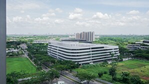 A modern building with a curved facade, surrounded by greenery and a clear sky. - Comfortable And Simply Studio At Sky House Bsd Apartment (Pagedangan)