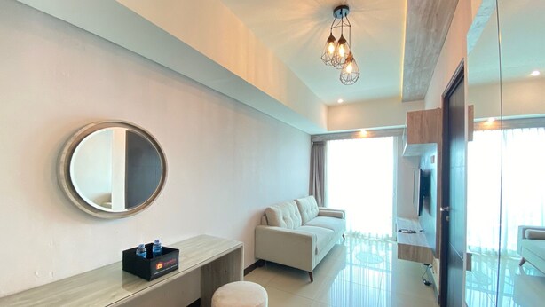 Un salon moderne avec un canapé, des poufs, un miroir rond et une console.