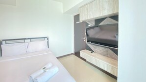 Une chambre d’hôtel avec un lit, une télévision et une armoire.