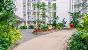 Un immeuble résidentiel doté de nombreux balcons, d’un jardin aménagé avec différentes espèces de plantes et d’une borne d’incendie rouge.
