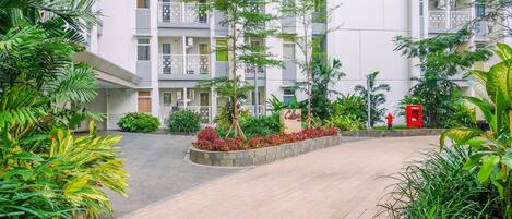 A residential building with multiple balconies, a landscaped garden area with various plants, and a red hydrant.