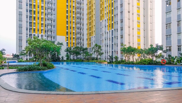 Une piscine entourée de verdure et de grands immeubles résidentiels dotés de balcons.