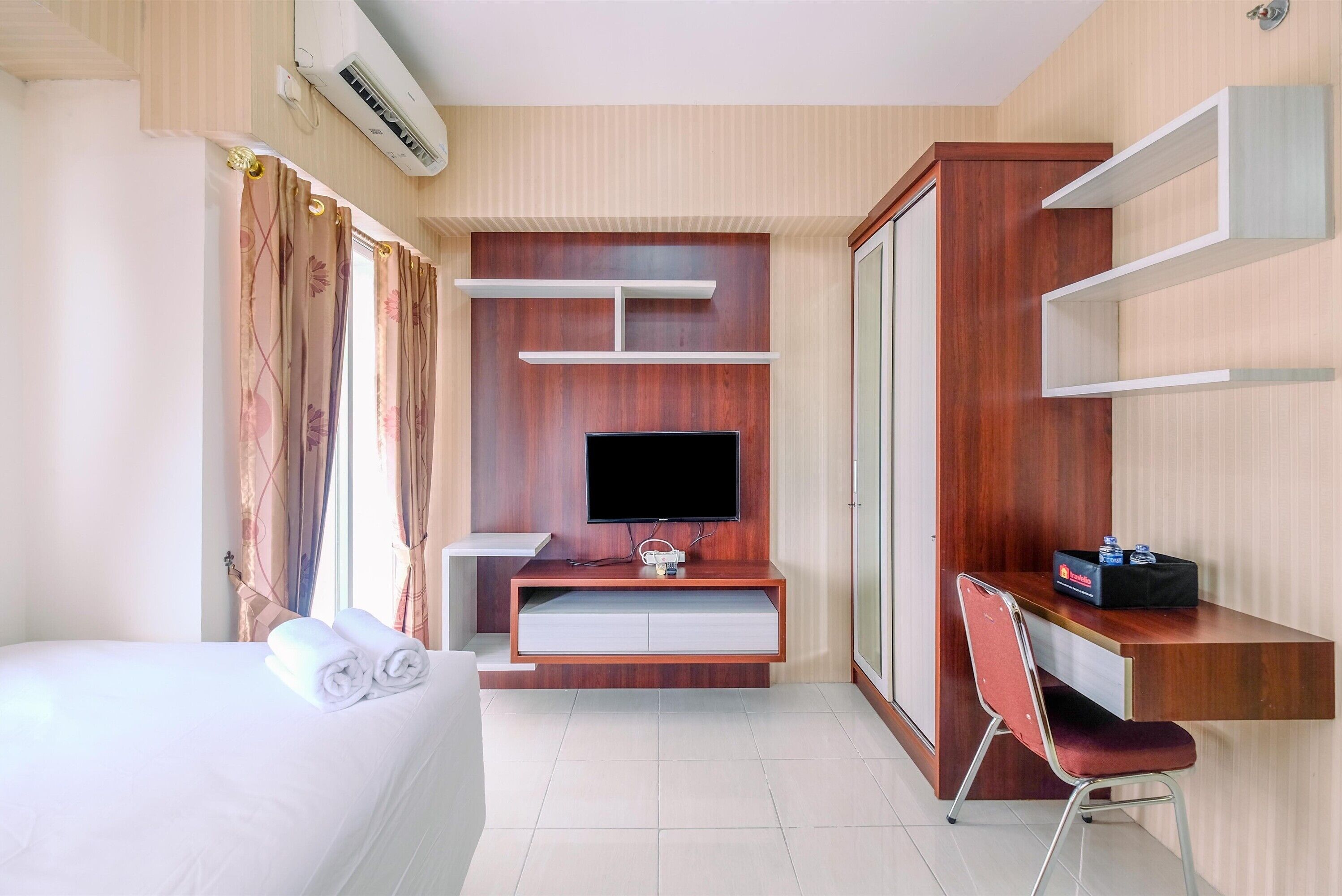 A hotel room with a bed, a desk, a TV, and a chair.