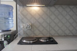 Modern kitchen with induction cooktop, water dispenser, and tiled backsplash.