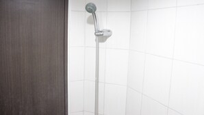 A shower with a handheld showerhead and a flexible hose, mounted on a wall with white tiles.