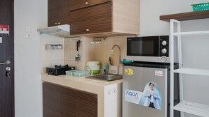 A modern kitchen with wooden cabinets, a microwave, a refrigerator, and a sink. - Comfortable And Simply Studio At Serpong Greenview Apartment (South Tangerang)