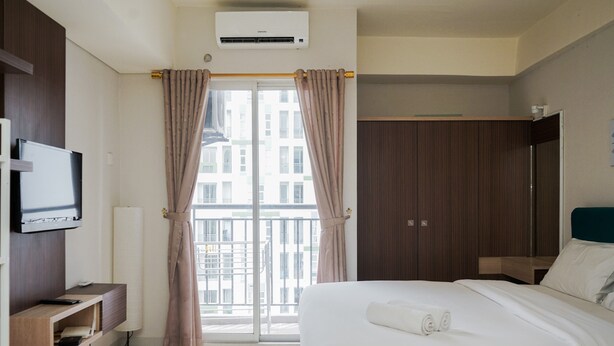 A hotel room with a bed, a TV, a desk, and a window with curtains. - Comfortable And Simply Studio At Serpong Greenview Apartment (South Tangerang)