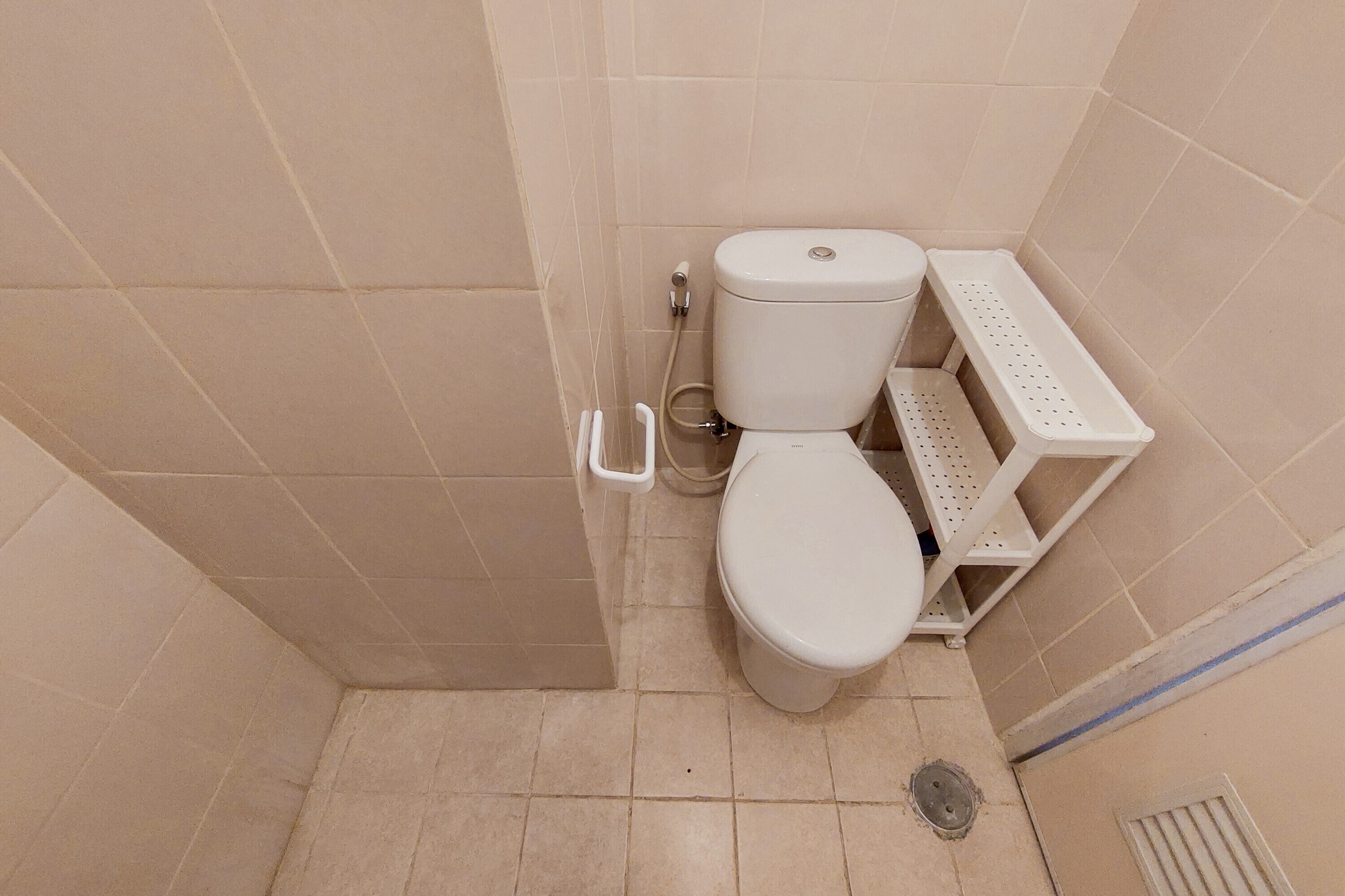 A small, clean bathroom with a toilet, a sink, and a shelf.
