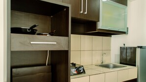 A compact kitchen with a built-in microwave, a sink, and a stove. - Elegant And Homey Studio At Paramount Skyline Apartment (Gading Serpong)