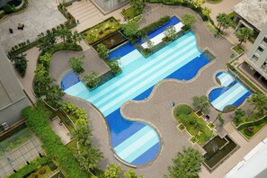 An aerial view of a hotel with multiple swimming pools, landscaped gardens, and a central courtyard. - Cozy Stay 2Br Green Bay Pluit Apartment (Jakarta)