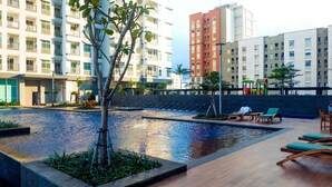 A rooftop pool area with lounge chairs and a children's play structure. - Comfort And Elegant 1Br Green Bay Condominium Apartment (Jakarta)