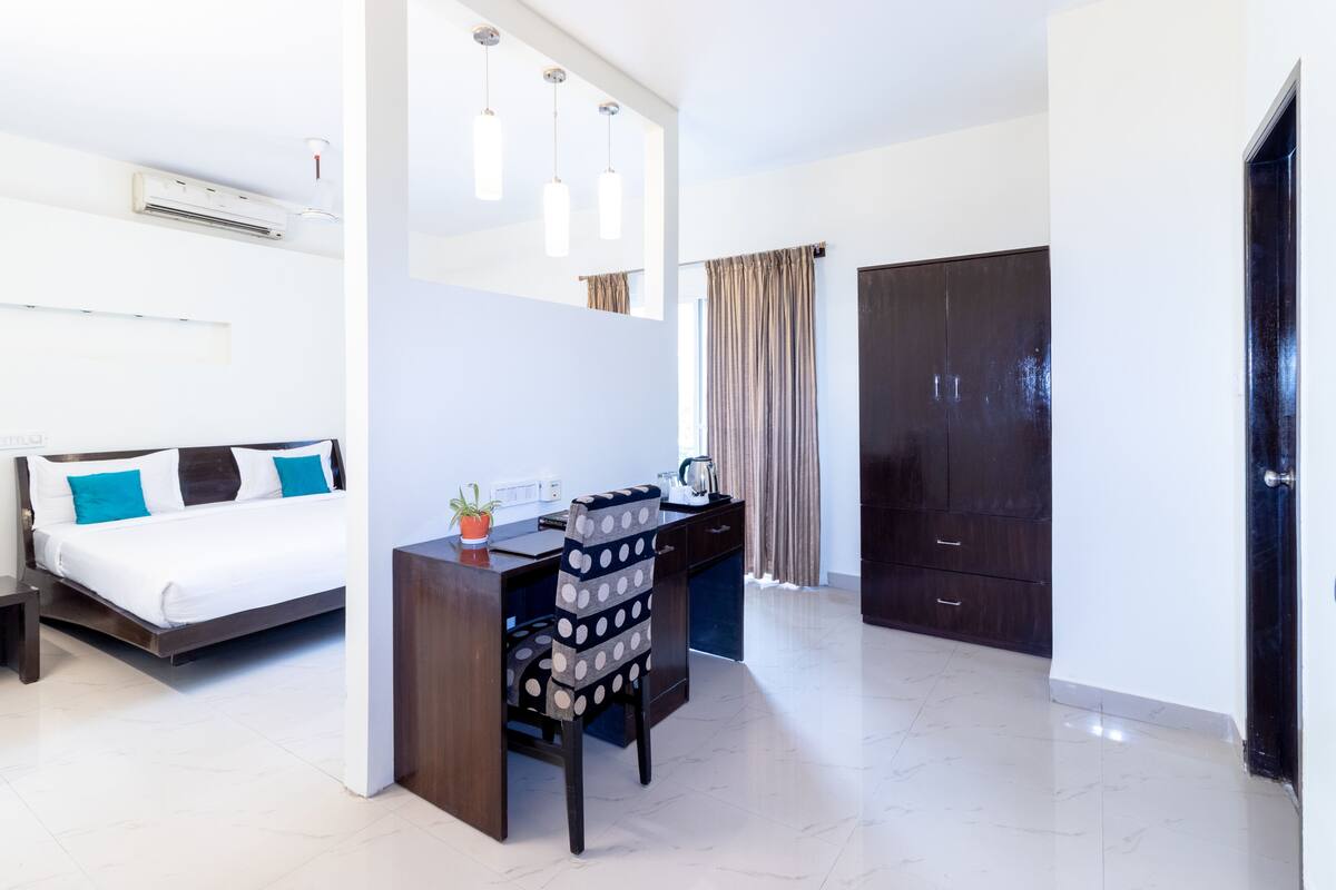 Een moderne hotelkamer met een bed, bureau, stoel, kledingkast en een airconditioning.