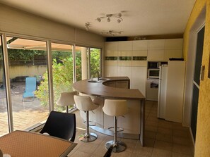 A compact kitchen with a bar area, a dining table with chairs, and a view of the outdoors. - Villa with private staircase feet in the water Solenzara area (Travo)