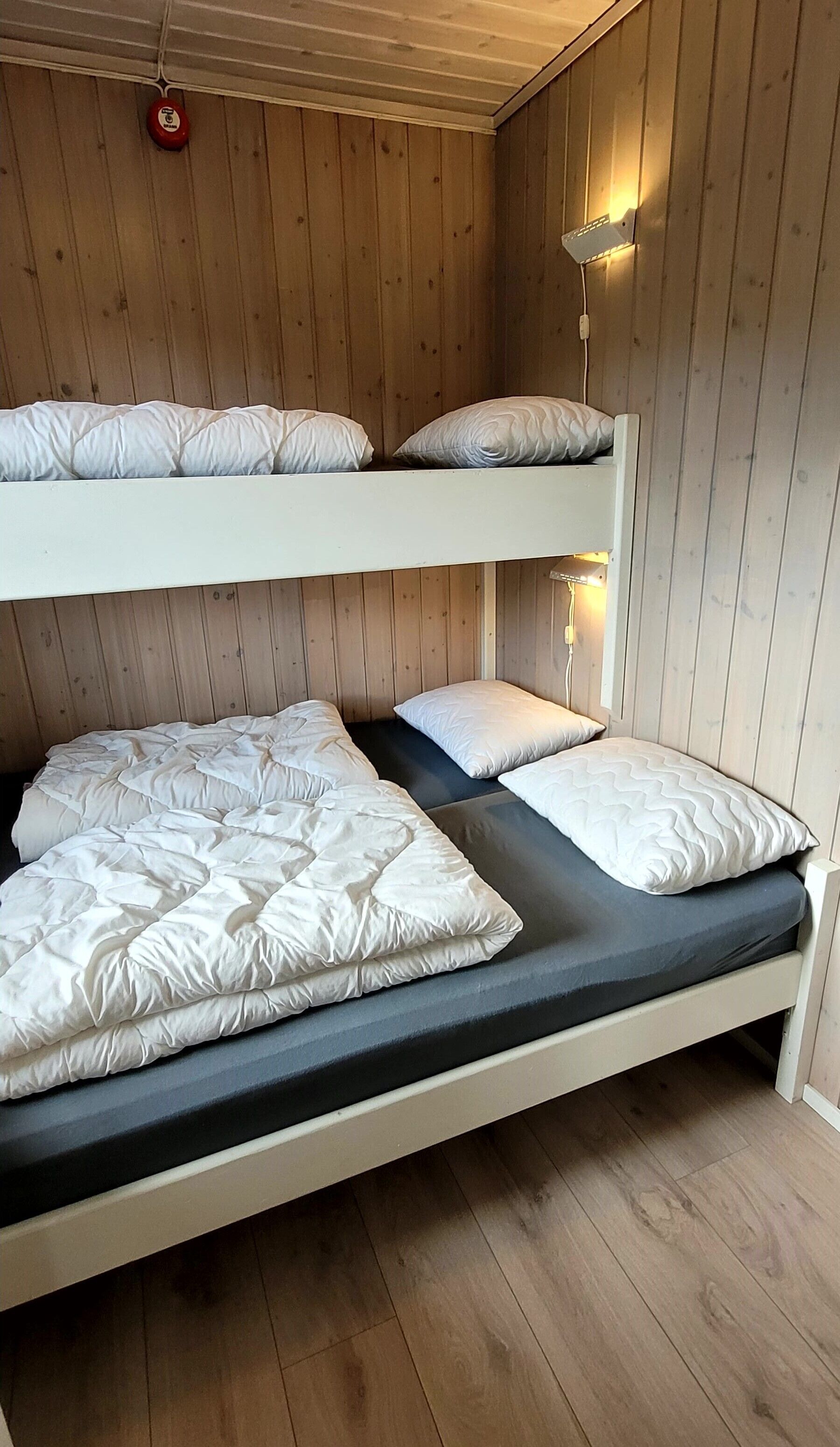 Un lit superposé à deux niveaux, chaque niveau étant équipé d’oreillers et d’un matelas.
