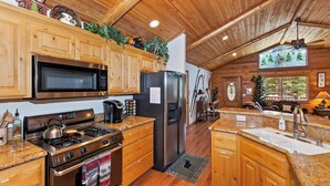 A kitchen with wooden cabinets, a stainless steel stove, a refrigerator, and a microwave.