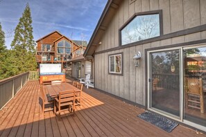 Eine Holzterrasse mit Tisch, Stühlen und einem Whirlpool, sowie eine große Glasschiebetür.