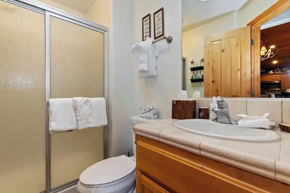 Un baño con ducha, inodoro, lavabo y armarios de madera.