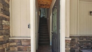 A stone exterior wall, a wooden door, and a staircase leading inside. - Wonderful Moonridge Location! Mountain Views! Hot Tub! Pool Table! Spacious Deck! (Big Bear Lake)