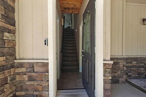 A stone exterior wall, a wooden door, and a staircase leading inside. - Wonderful Moonridge Location! Mountain Views! Hot Tub! Pool Table! Spacious Deck! (Big Bear Lake)